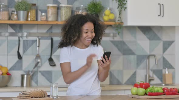 Young African Woman Doing Video Call on Smartphone in Kitchen