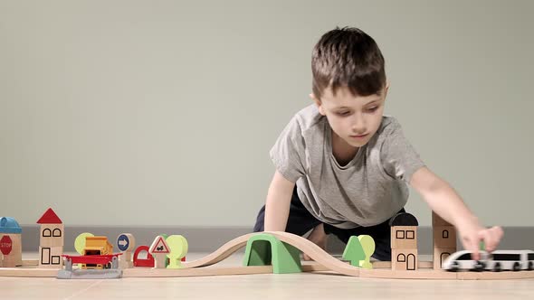 Cute boy plays with a wooden train, takes him across the bridge on flights. Wooden educational toys