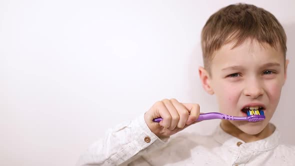 Little boy brushing his teeth on a white background