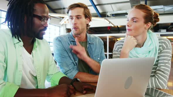 Colleagues interacting with each other over laptop