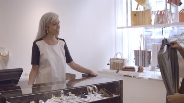 Serious Latin Woman Buying Clothes in Fashion Store