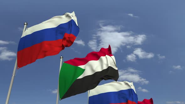 Waving Flags of Sudan and Russia on Sky Background alt