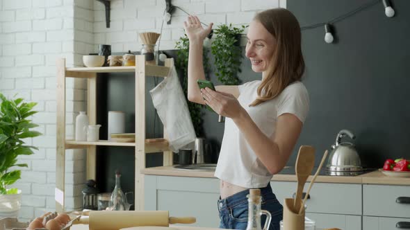 Female Celebrate Online Win or Victory on Smartphone Standing at Kitchen