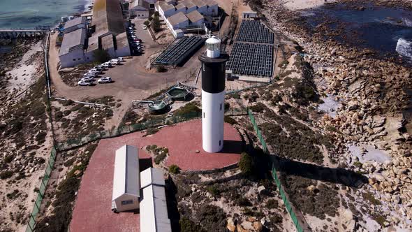 Drone pullback reveals black and white lighthouse in Doringbaai, Weskus