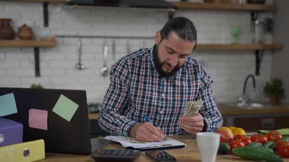 Happy Handsome Middle Eastern Man Counting Cash Dollars Using Calculator Smiling