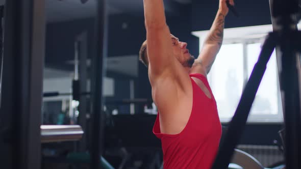 Male Training Back Muscles Doing Pulls Weight Exercise in a Gym