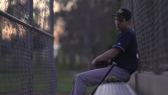 A baseball player resting on the bench.