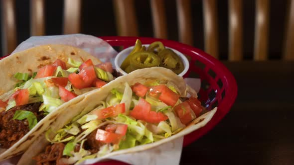 Tabletop shot of beef soft tacos in flour tortillas with pickled jalapenos on the side, slider 4K