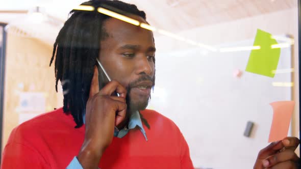 Man talking on mobile phone while looking at sticky notes