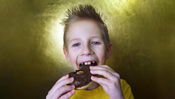 Happy kid eating a chocolate donut. Portrait of a boy with a face in chocolate