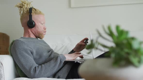 Albino african american man with dreadlocks using tablet and headphones