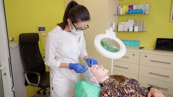 Beautician Making Botox Injection with Botulinum Toxin Into Forehead of Young Woman