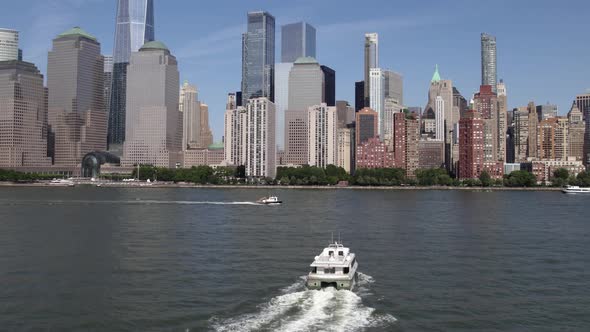 Aerial view over a boat moving towards the Lower Manhattan skyline, in NYC, USA - rising, drone shot