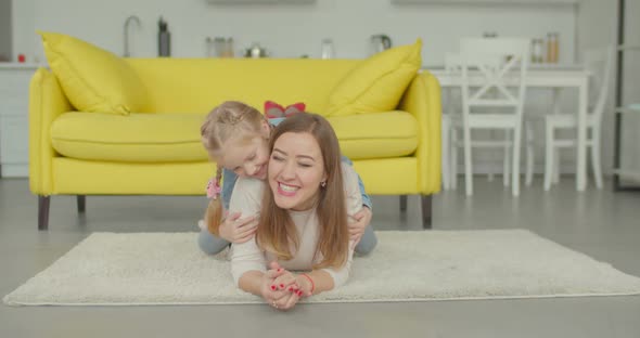 Excited Cute Girl Piggybacking Mom on the Floor