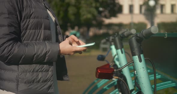 Woman Take Electric Kick Scooter or Bike Bicycle in Sharing Parking Lot Tourist Phone Application