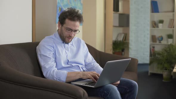 Man With Eyeglasses Sitting on Sofa and Shopping Online on Laptop, Technologies