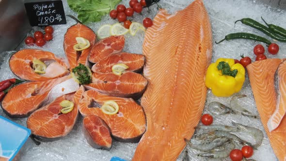 Composition of Trout and Salmon Steaks Lies on Ice in Showcase of Supermarket