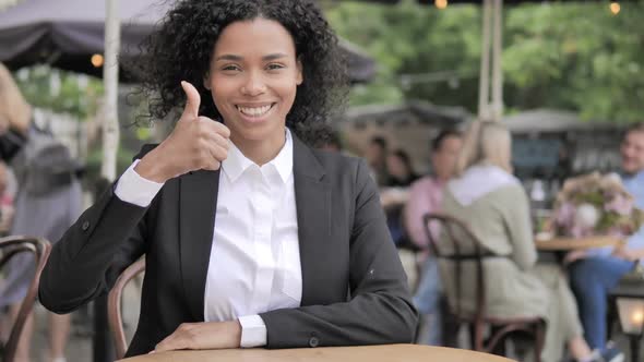 Thumbs Up By African Businesswoman Sitting in Outdoor Cafe