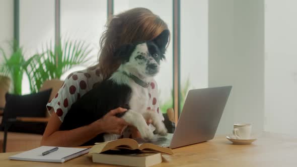 Happy Woman Typing on Laptop Along with Her Cheerful Dog Have Fun Time