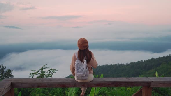 Young woman travelers looking at the sunrise and the sea of mist on the mountain in the morning