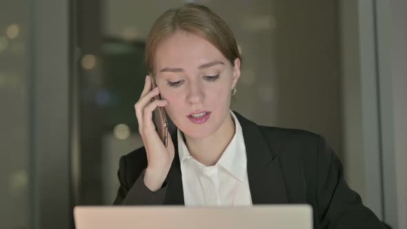 Close Up of Businesswoman Talking on Cellphone on Office Desk at Night