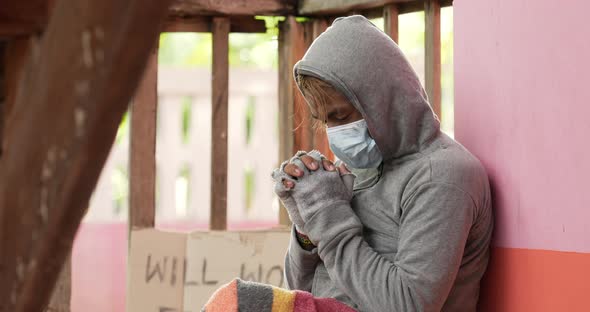 Homeless man in face mask is praying