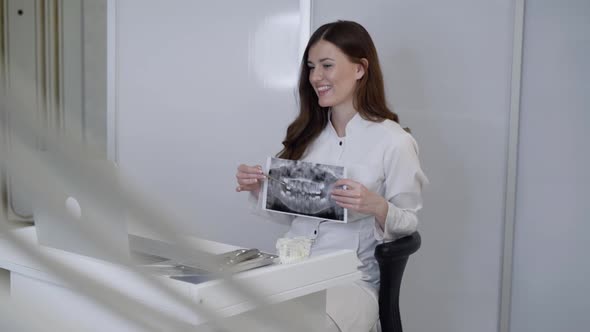 Happy Female Dentist Conducts an Online Consultation at Laptop Using Jaw Xray