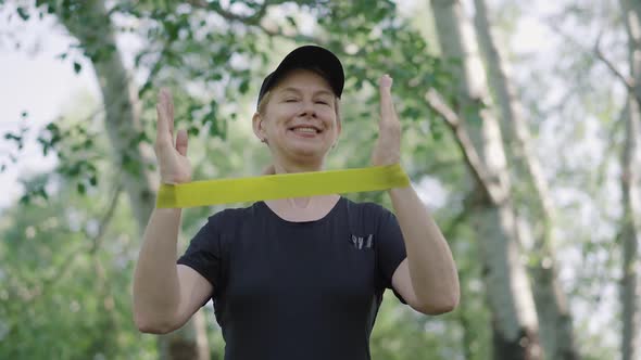 Happy Mid-adult Sportswoman Training Hands Stretching Resistance Band. Portrait of Cheerful