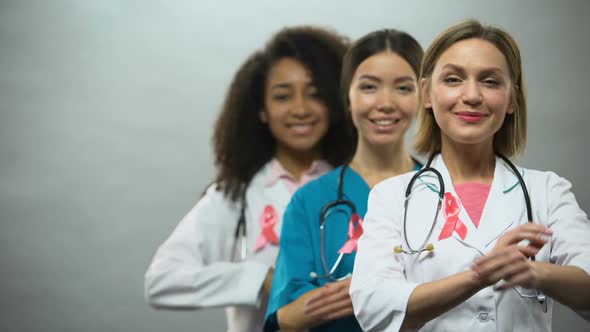 Smiling Multiracial Nurses With Pink Ribbons, International Breast Cancer Sign