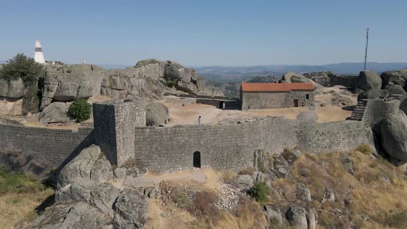 Tourist woman greeting from Monsanto castle ruins in Portugal. Aerial backward