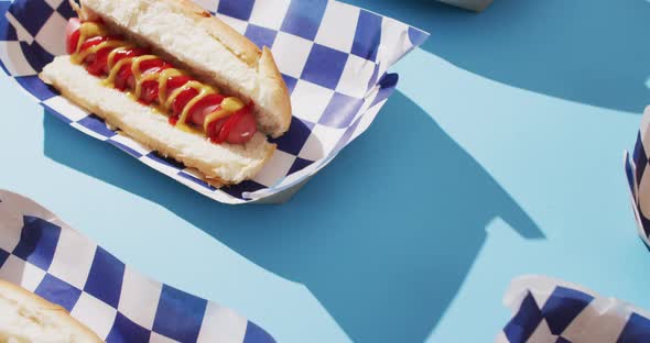 Video of hot dogs with mustard and ketchup on a blue surface