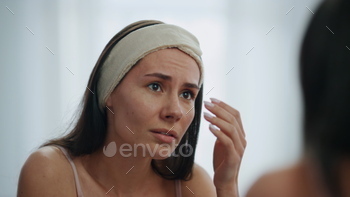 ection at home. Closeup dissatisfied lady worry about first wrinkles at bathroom. Unhappy woman nervous of skincare product effect or face condition