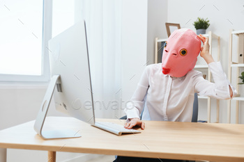 n pink fish mask work on computer online pondering or making decision thinking of problem solution touch head in light modern office. Copy space