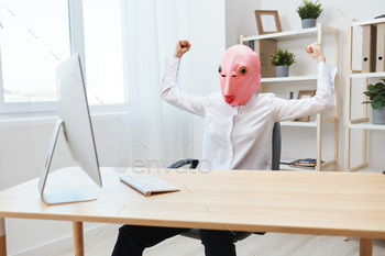 in pink fish mask work on computer online showing muscles in light modern office. Copy space