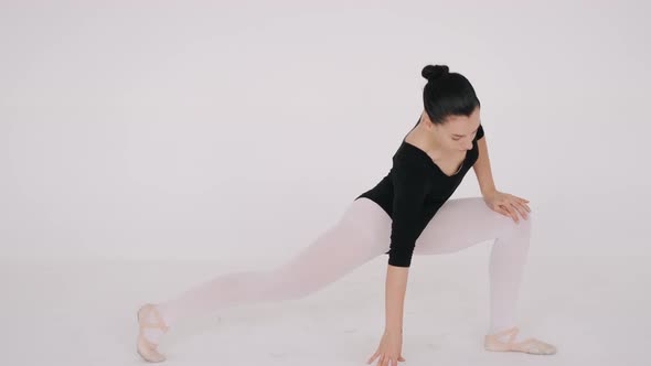 Fit Young Ballerina Stretching in White Dance Studio Isolated