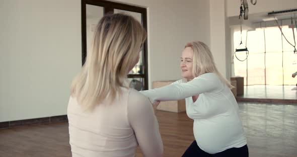 Pregnant Woman and Her Personal Trainer Doing Stretching Exercises