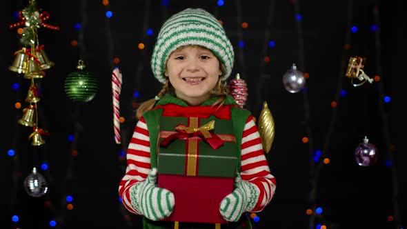 Kid Girl Christmas Elf Santa Helper Giving Present Gift Box To Camera