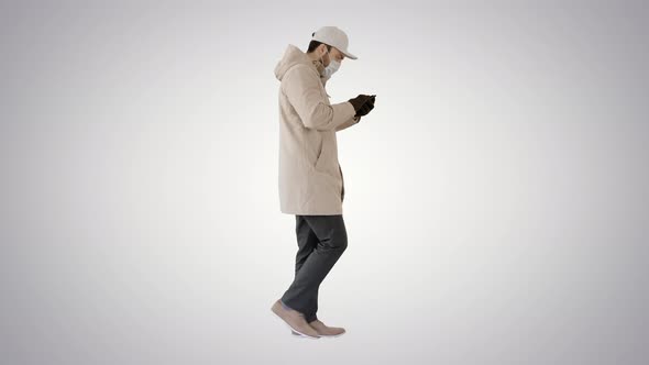 Caucasian Man in a Medical Mask Walking and Using the Phone on Gradient Background.