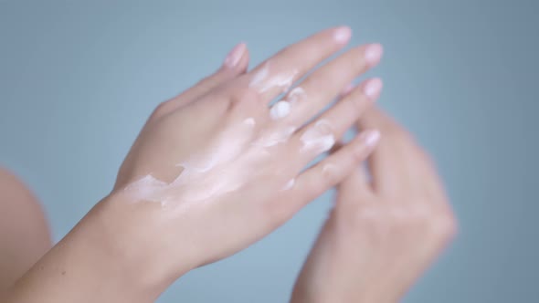 Close Up View of Female Person with Nude Finger Nails Color Putting and Massaging Cream on Hands