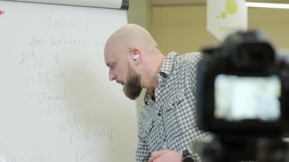 Teacher Records Video Lessons He Stands and Writes with a Pen on a Flip Chart