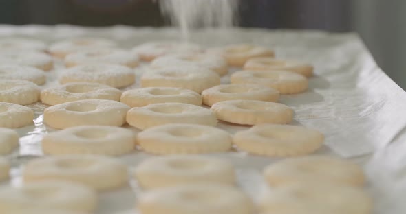 Baker preparing butter cookies with strawberry jam and powdered sugar