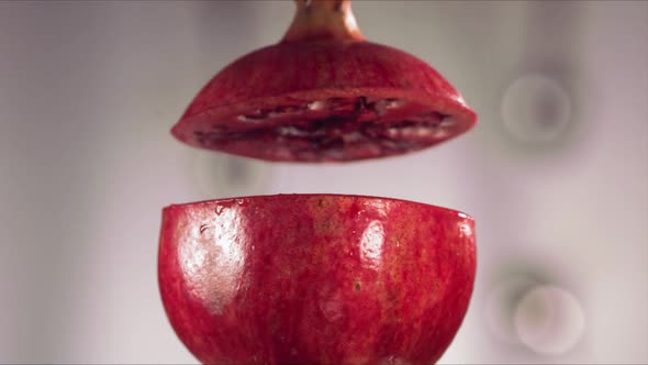 Half Pomegranate Falling and Splashing on White Background