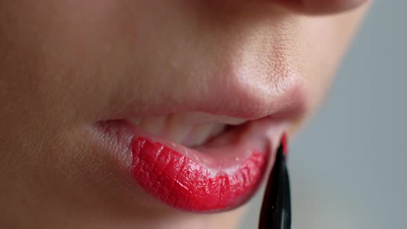 The Girl Does Makeup on Her Lips. Applying Red Lipstick To Lips. Close-up.