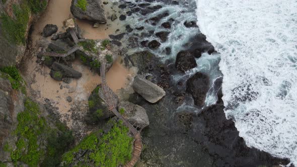 Top down aerial view of giant ocean waves crashing and foaming in coral beach