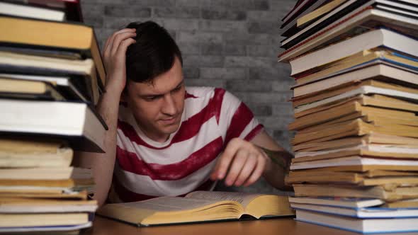 Man Student Boring Reading Book at Library with a Lot of Books in University. Student Disheartened