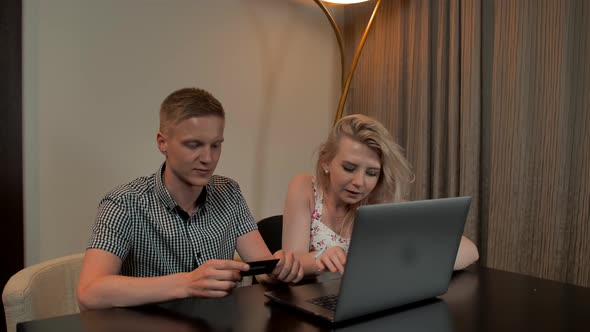 Attractive Guy and Girl Sit on the Coucand Shop Online with Credit Card on the Laptop Notebook.