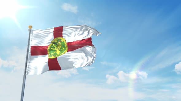 Flag of Alderney waving in the wind with blue Sky