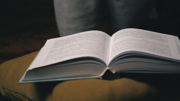 Cute Girl Reads and Leafs Through a Book While Lying Comfortably in Bed