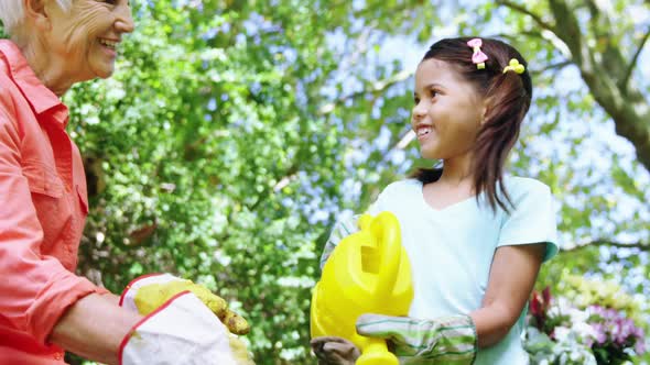 Grandmother and grand daughter watering plants