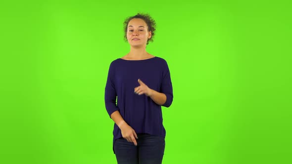 Curly Woman Listening Attentively and Nodding His Head Pointing Finger at Viewer. Green Screen